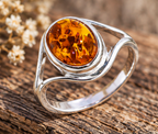 Bague en ambre ovale et argent massif 925 posée sur du bois